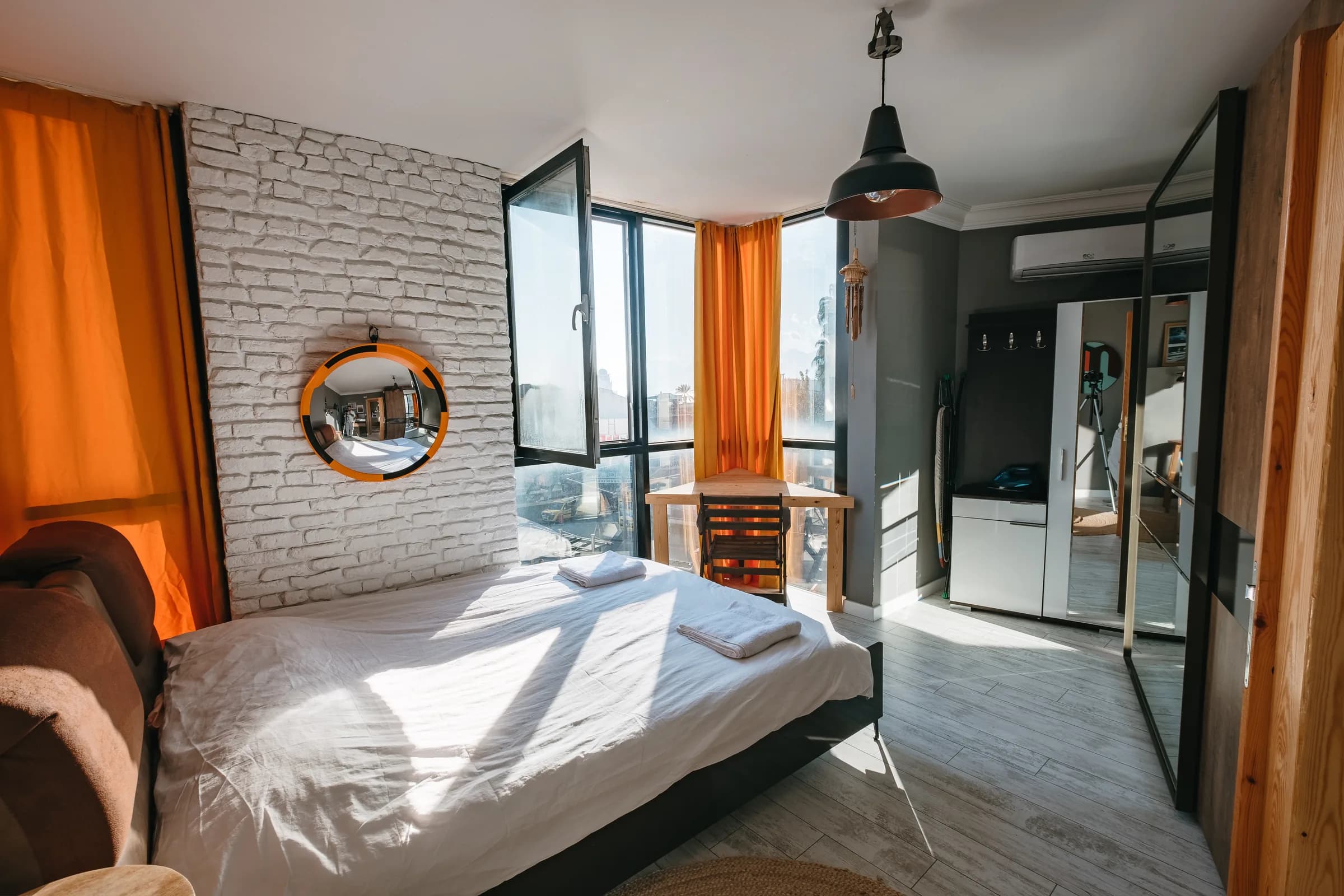 Slaapkamer met bakstenen wand en ronde spiegel