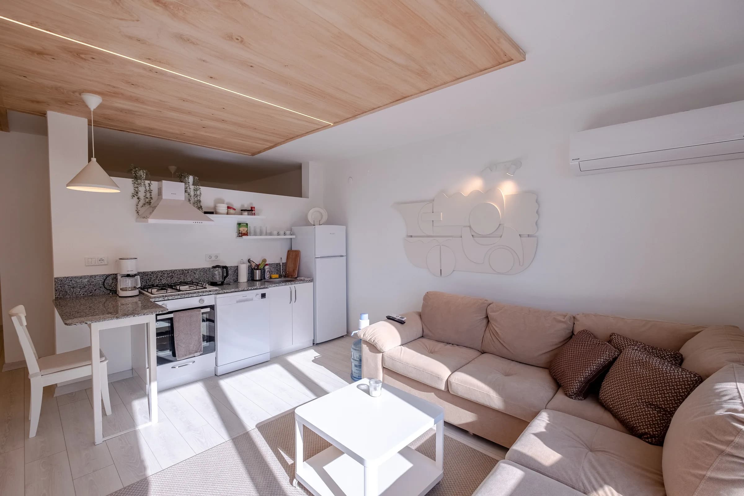 Woonkamer en keuken onder een houten plafond met lichtlijn