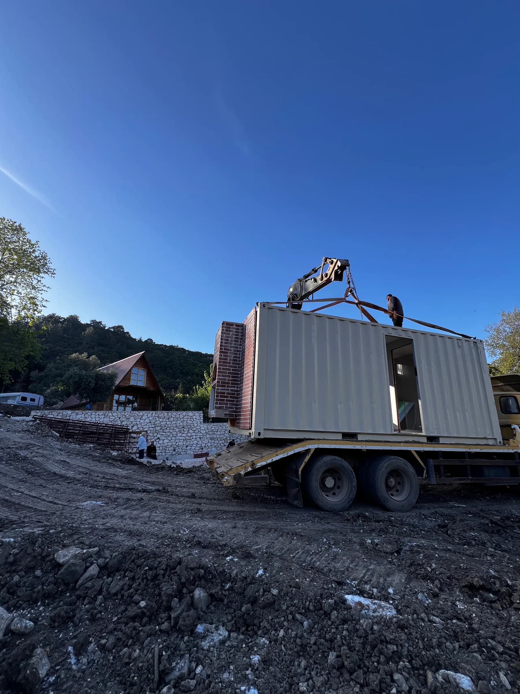Een container wordt met een kraanwagen op de bouwplaats geleverd