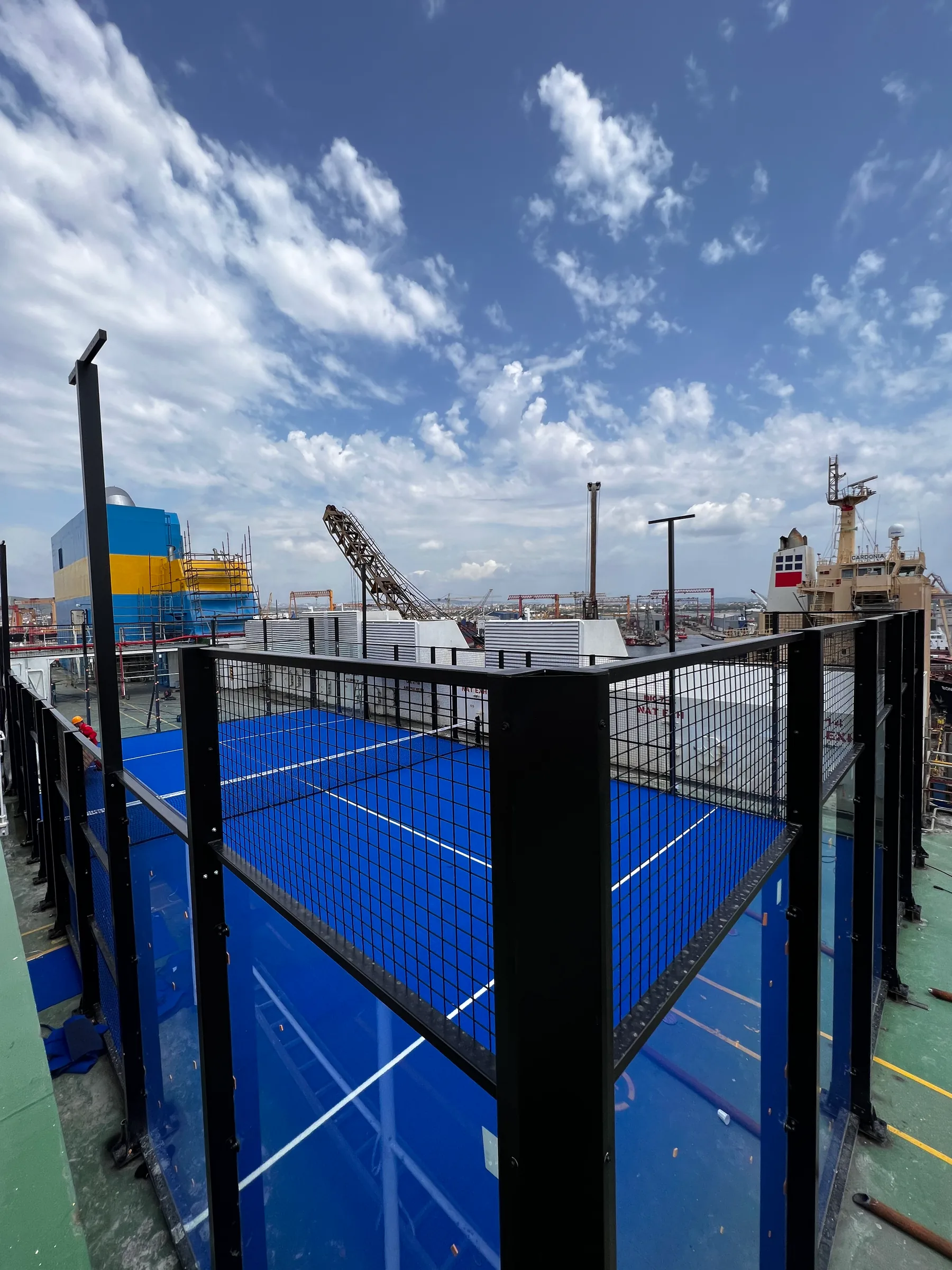 De padelbaan op het dek, met de scheepswerf op de achtergrond