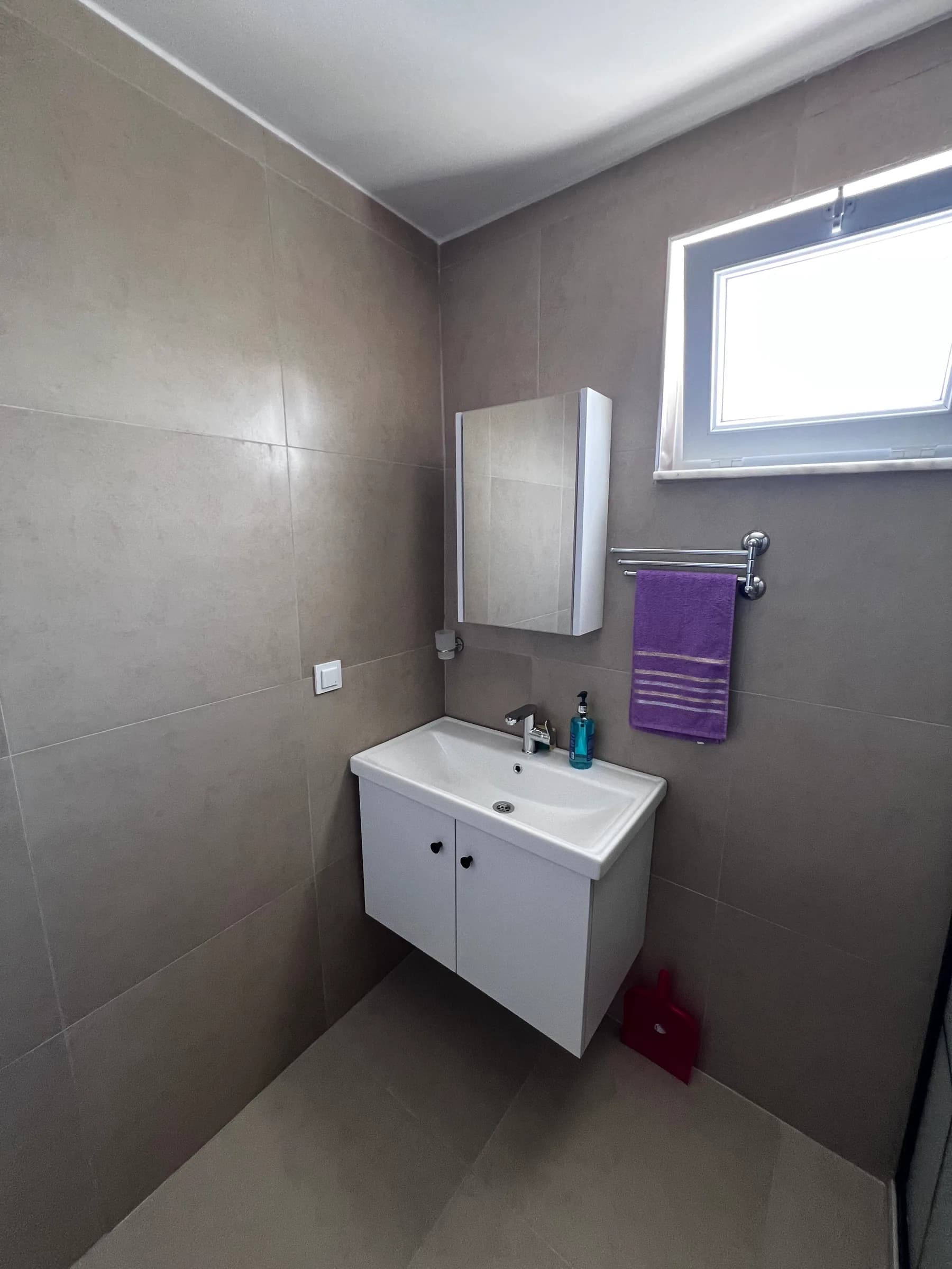 Badkamer met grote wandtegels en zwevend badmeubel
