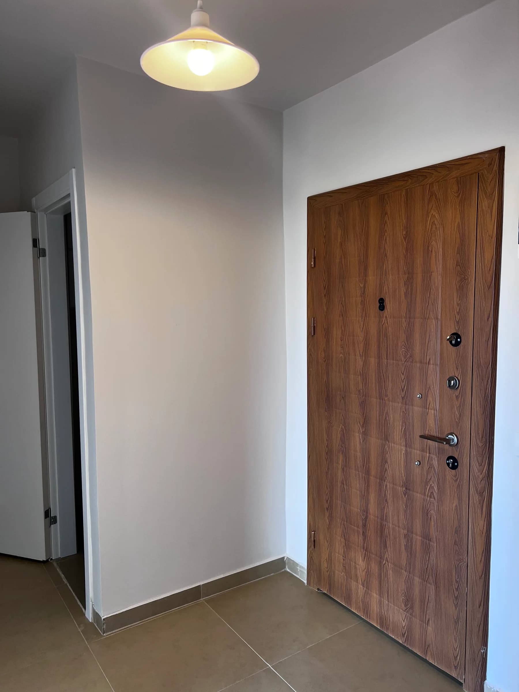Hal met houten voordeur en nieuwe vloertegels