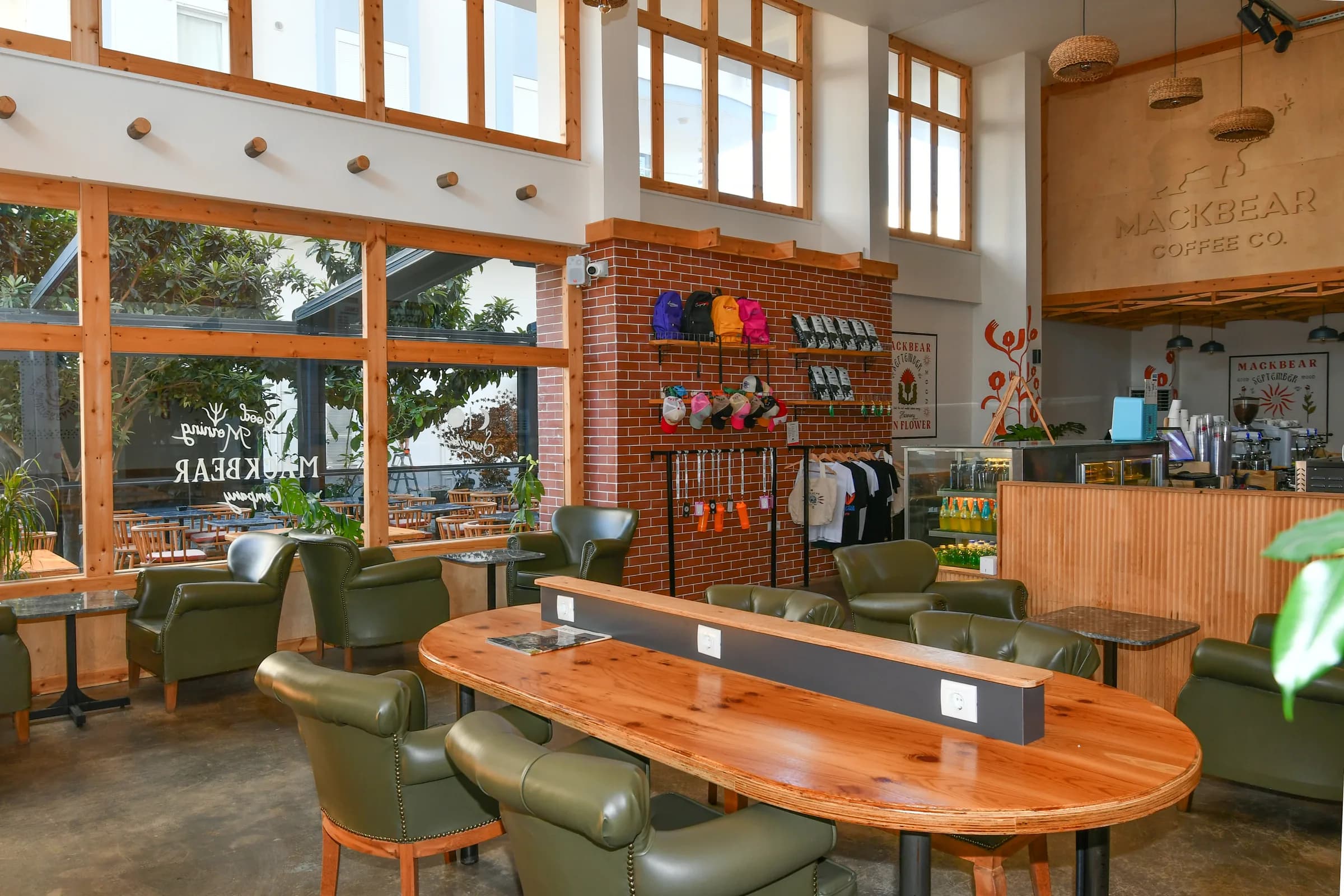 Interieur met lange houten tafel, groene leren fauteuils en bakstenen wand
