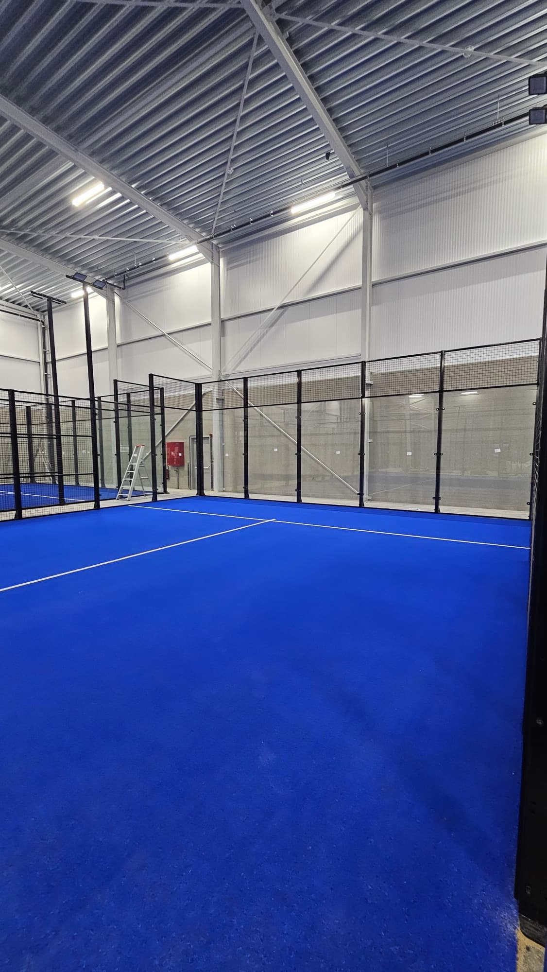 Afgemonteerde padelbaan met blauw speelveld en hekwerk
