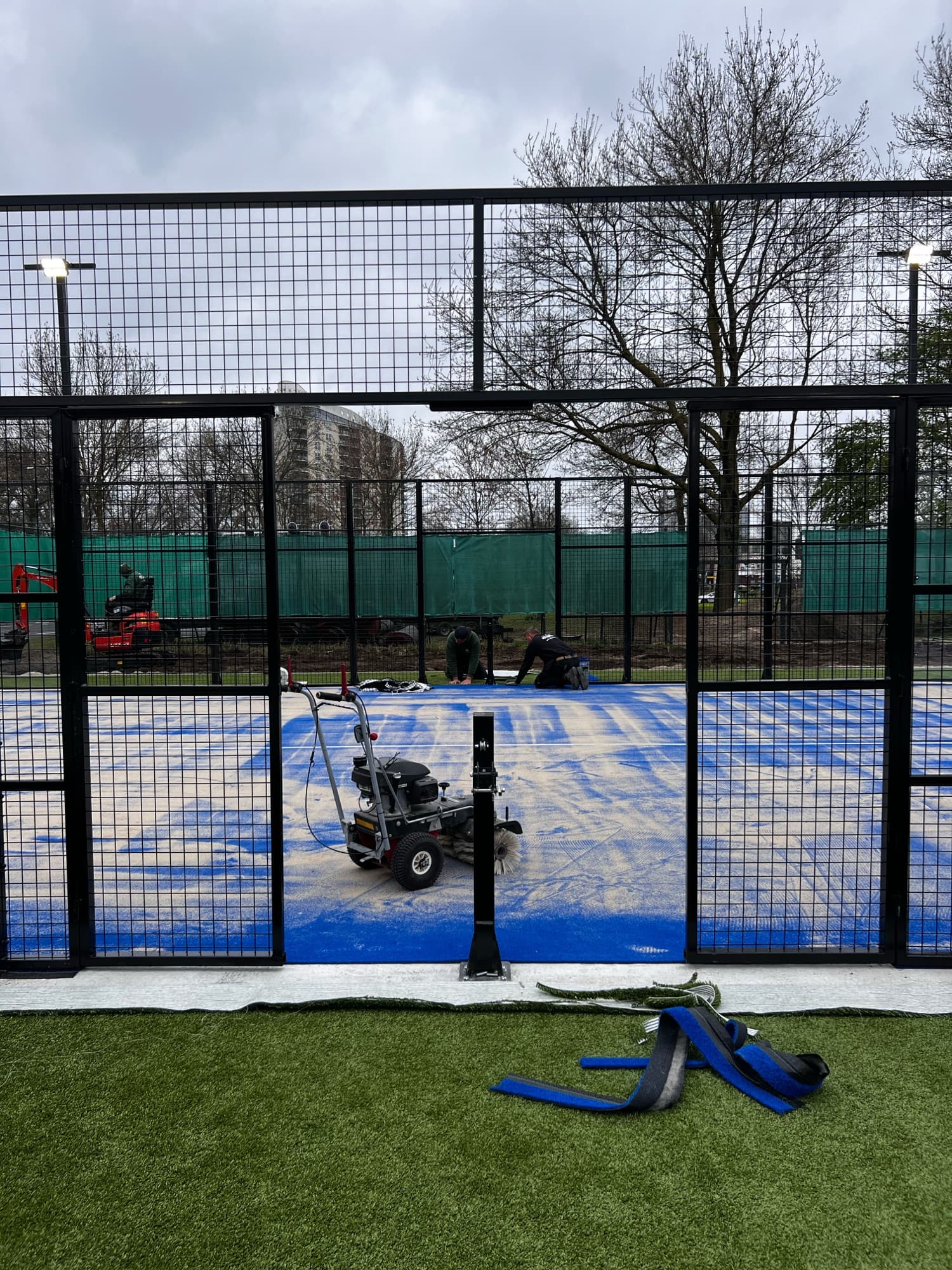 Aanbrengen van het blauwe kunstgras op de padelbaan