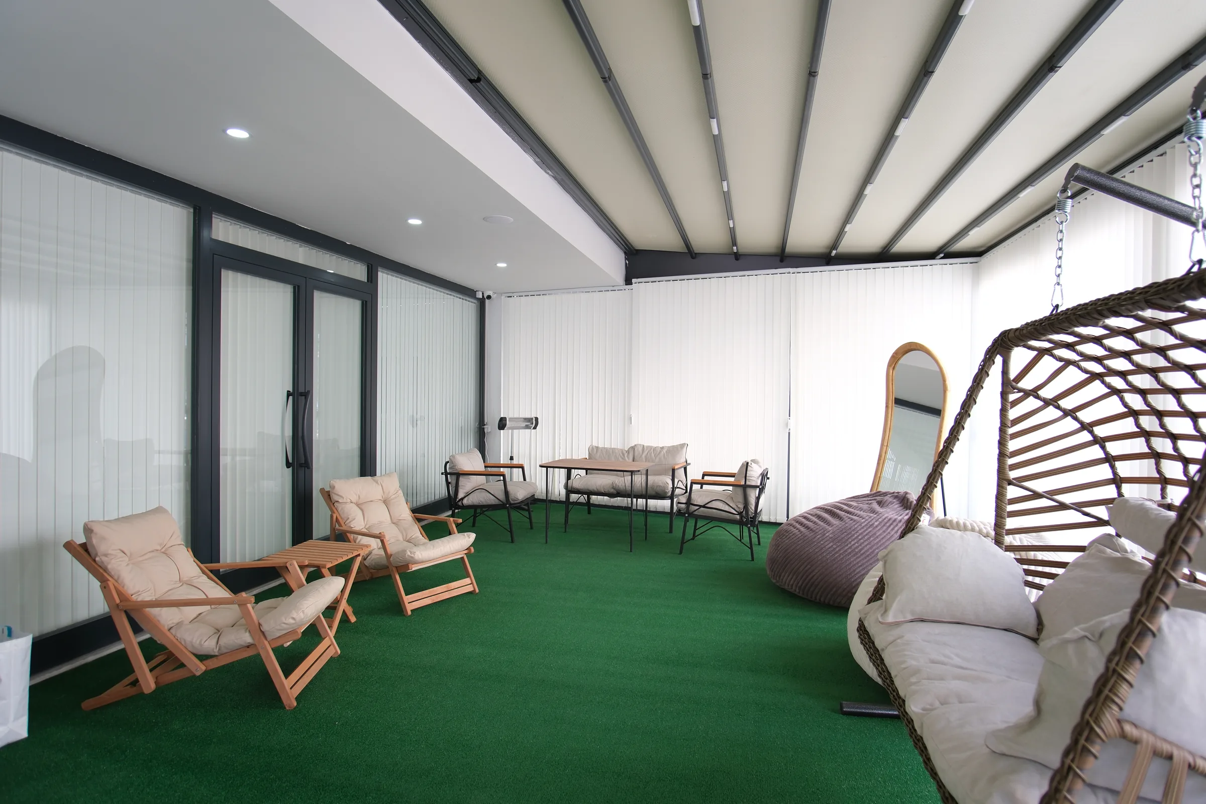 Lounge met groene vloer, loungestoelen en hangstoel